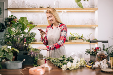 free time, leisure time of young florist female at work, look at smartphone, chatting with friend,...