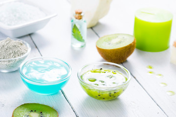 beauty products with kiwi fruit ingredient on white wooden table