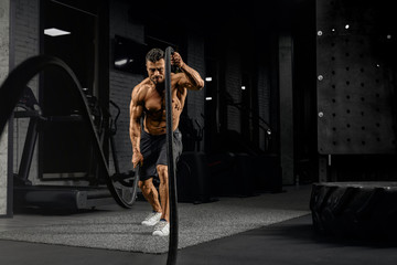 Muscular man doing battle rope training.
