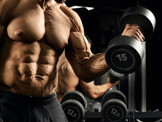 Fototapeta na wymiar Male bodybuilder training biceps with dumbbell.