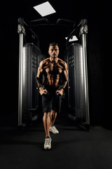 Fototapeta na wymiar Muscular bodybuilder doing crossover chest exercise.
