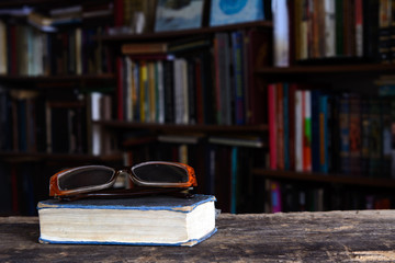 glasses are on the book. On a blurred background - books. Concept - Education, Library, College