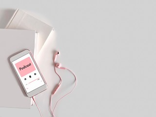 A mobile phone is playing Podcast. Listening to Podcast concept with books and earphone on white background.