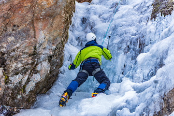 Ice Climbing Man with an Ice Axe and Crampons on a Frozen Waterfall in the Taschachschlucht...