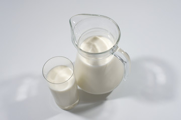 Milk in a glass with a jug on a gray background. Side view. Milk product.