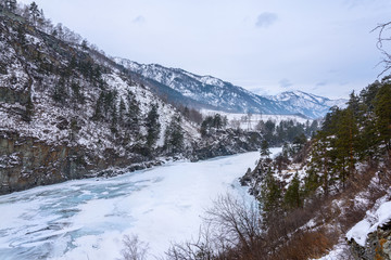 Landscape with snow-capped mountains and a freezing mountain river