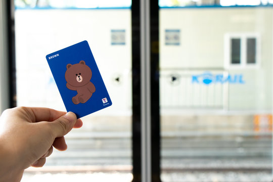 Seoul, South Korea- Oct 21, 2019  : Traveller hand hold t money card with line cartoon character on defocused Korail clear door for train transportation
