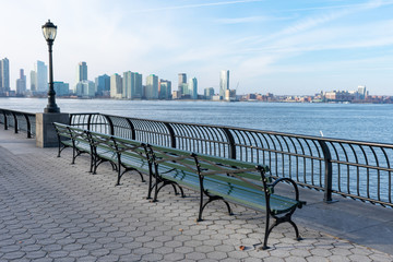Empty Bench at Battery Park in New York City with a view of the Jersey City Skyline along the...