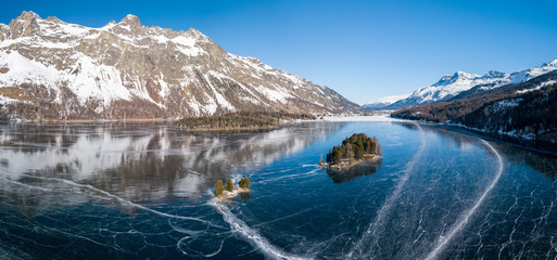Aerial panorama image of the Chaviolas islets on the frozen lake of Silsersee in St. Moritz,...