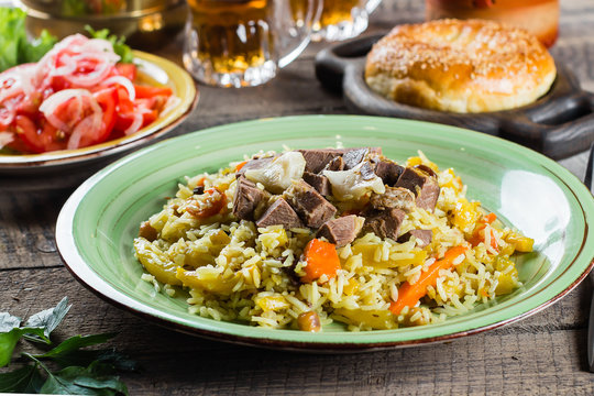 National Traditional Uzbek pilaf with meat and rice on a wooden table. Oriental cuisine concept. Close-up image