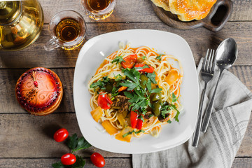 Traditional asian uzbek noodle lagman with vegetables and meat on rustic wooden table background. Top view