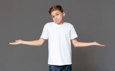 Unsure teenager boy shrugging with empty palms, hard choice