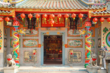Fototapeta na wymiar Chinese shrine. A beautiful architectural details of the Chinese shrine's entrance, decorated with golden dragon on both side. Chinese character means name of the shrine.