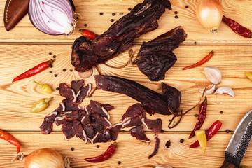 Jerky on a wooden background with vegetables, and hunting knife