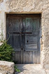 Fototapeta na wymiar Closed old wooden door, padlock. Old stone wall, sunny day.