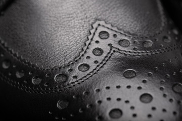 Black leather shoes against wooden background.