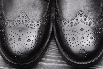 Black leather shoes against wooden background.