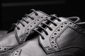 Black leather shoes against wooden background.
