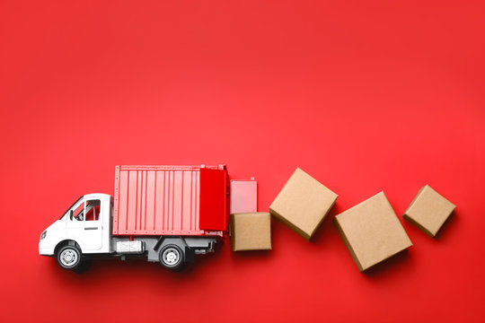 Top view of toy truck with boxes on red background. Logistics and wholesale concept