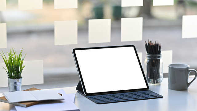 Blank Screen Computer Tablet In A Leather-case And Keyboard Is Setting On A Modern Working Table Over Comfortable Office Background.