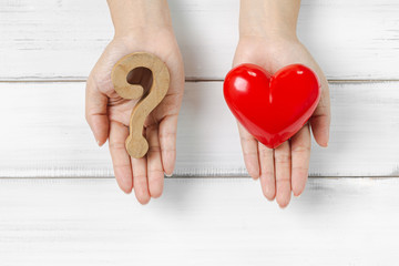 Woman Hands Hold Question Mark and Red Heart on white wood background. Solving Problem of Love...