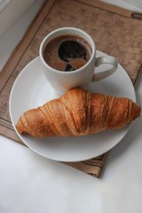 coffee and croissant  on a white plate for breakfast
