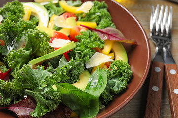 Tasty fresh kale salad on wooden table, closeup