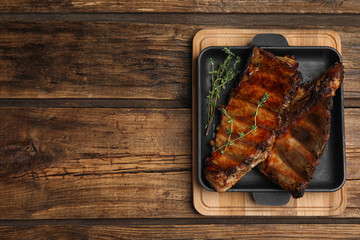 Tasty grilled ribs on wooden table, top view. Space for text