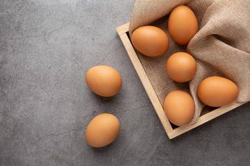 Chicken eggs in the wooden tray on the black cement floor. Top view.