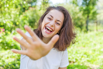 Happy girl smiling outdoor. Beautiful young brunete woman with brown hair resting on park or garden green background. European woman. Positive human emotion facial expression body language