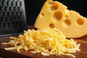 Tasty grated cheese on wooden table, closeup