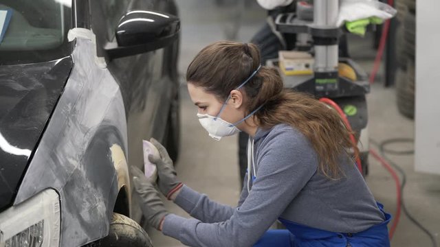 Apprentice working on car body shell in workshop