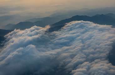 Flying over central highlands of Vietnam at dawn near the city of Da Lat. Clouds and mist reveal the  mountains below