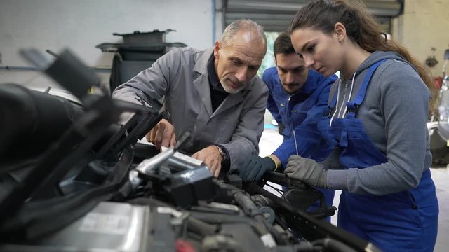 Instructor with trainees working on car engine 