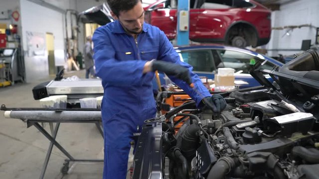Apprentice working on car engine in workshop