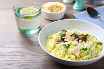 Delicious risotto with cheese and mushrooms on wooden table