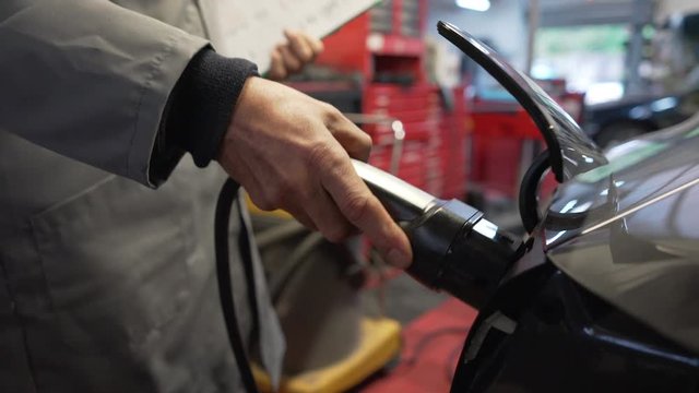 Carworker charging electric vehicle battery