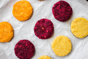 Raw Vegan chickpea burgers cutlets or patties. Healthy vegan diet food. Mixed vegetables yellow pumpkin, orange carrot, green spinach and red beet chickpea cutlets.