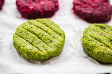 Raw Vegan chickpea burgers cutlets or patties. Healthy vegan diet food. Mixed vegetables yellow pumpkin, orange carrot, green spinach and red beet chickpea cutlets.