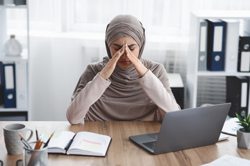 Exhausted arabic businesswoman having migraine after long time work in office