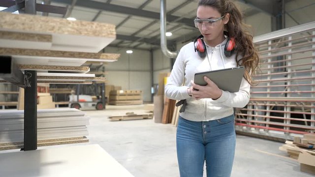 Young woman apprentice working in woodwork warehouse
