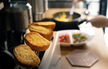 Selective focus of female cooking breakfast on kitchen counter bar