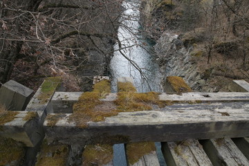  fragment old wooden ruined bridge covered with moss over a mountain river in the forest