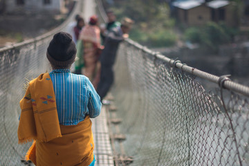 people crossing hanging bridge in nepal