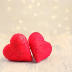 Fototapeta premium Two closeup love hearts on a wooden table and blurry defocused light bokeh background. Valentine's day greeting card. Love and holiday concept.Square, Copy space.