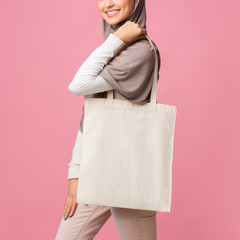 Mockup image of muslim girl holding blank canvas tote bag - obrazy, fototapety, plakaty
