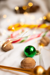  Green Christmas ball lies among walnuts and candies on a white background. Christmas atmosphere.