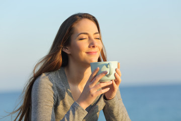 Satisfied woman drinking coffee at sunset