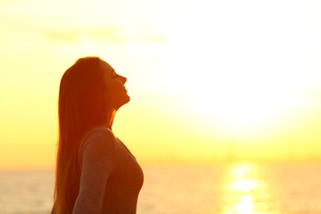Woman breaths fresh air at sunset on the beach