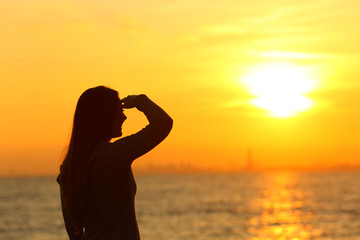 Woman searching with hand on forehead at sunset